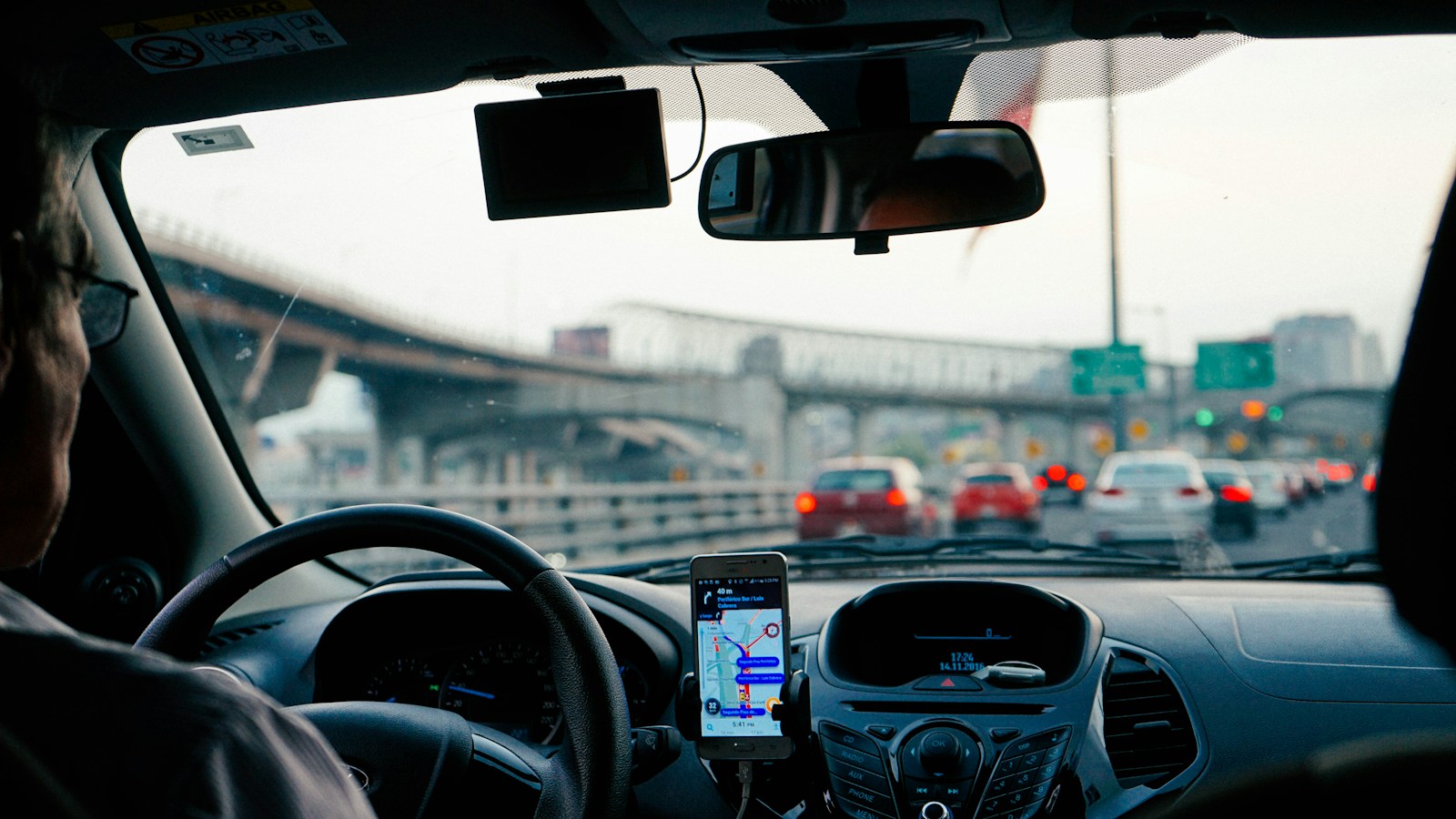 Motorista no trânsito da cidade com a navegação ligada no painel do carro